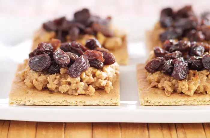 graham crackers topped with peanut butter and raisins